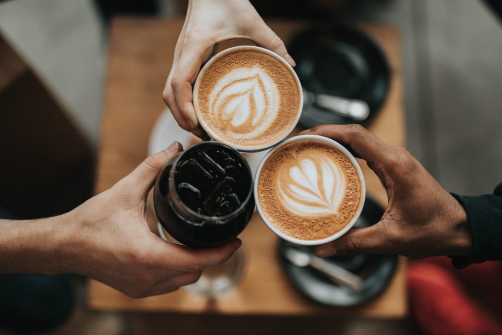 Three hands holding coffee cups touching