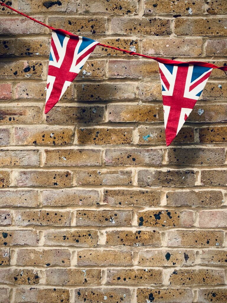 Union Jack flag bunting against a brown brick wall