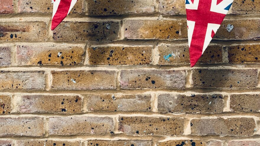 Union Jack flag bunting against a brown brick wall